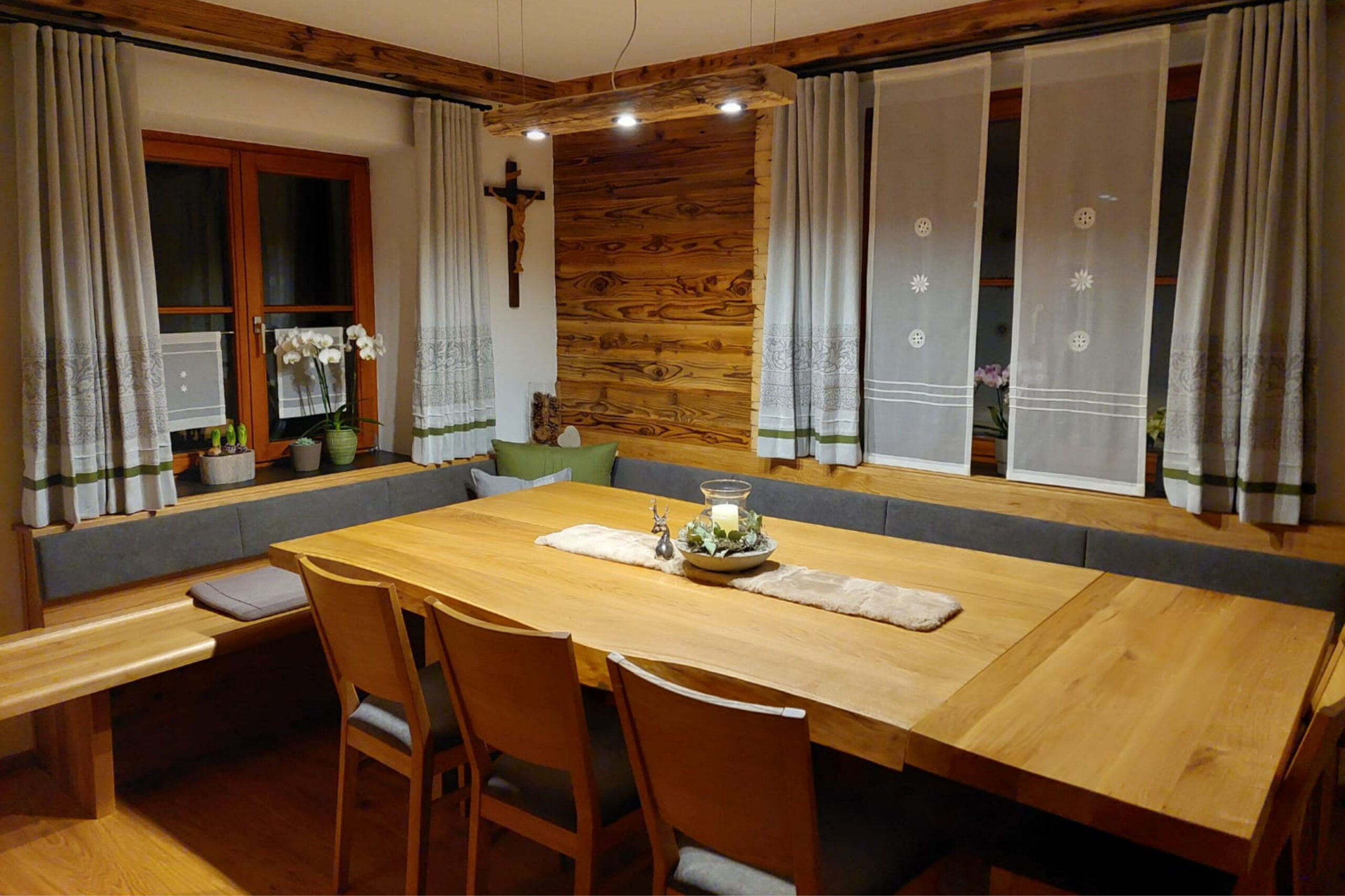 Esszimmer mit umlaufender Eckbank und langem Massivholztisch vor Holzwand